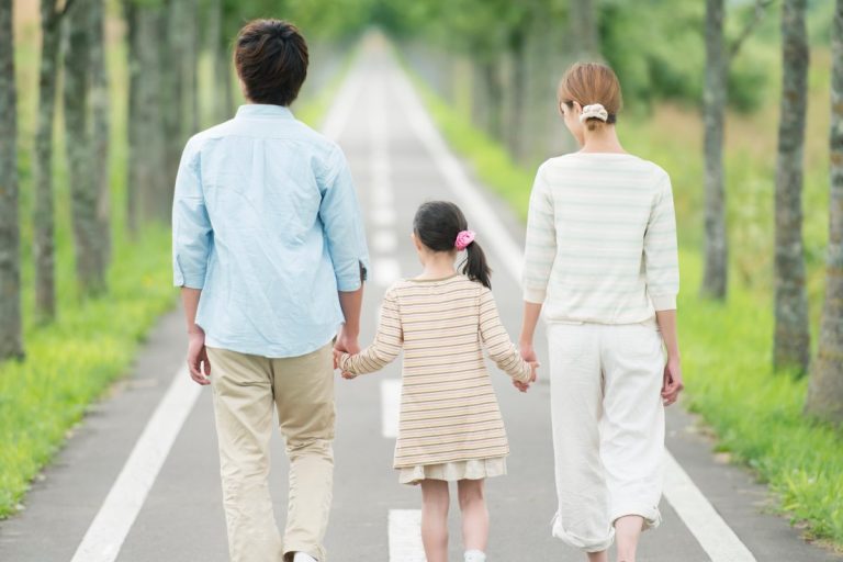 Eltern gehen getrennt mit ihrem Kind einen gemeinsamen Weg – Symbol für Co-Parenting und Trennung mit Verbindung