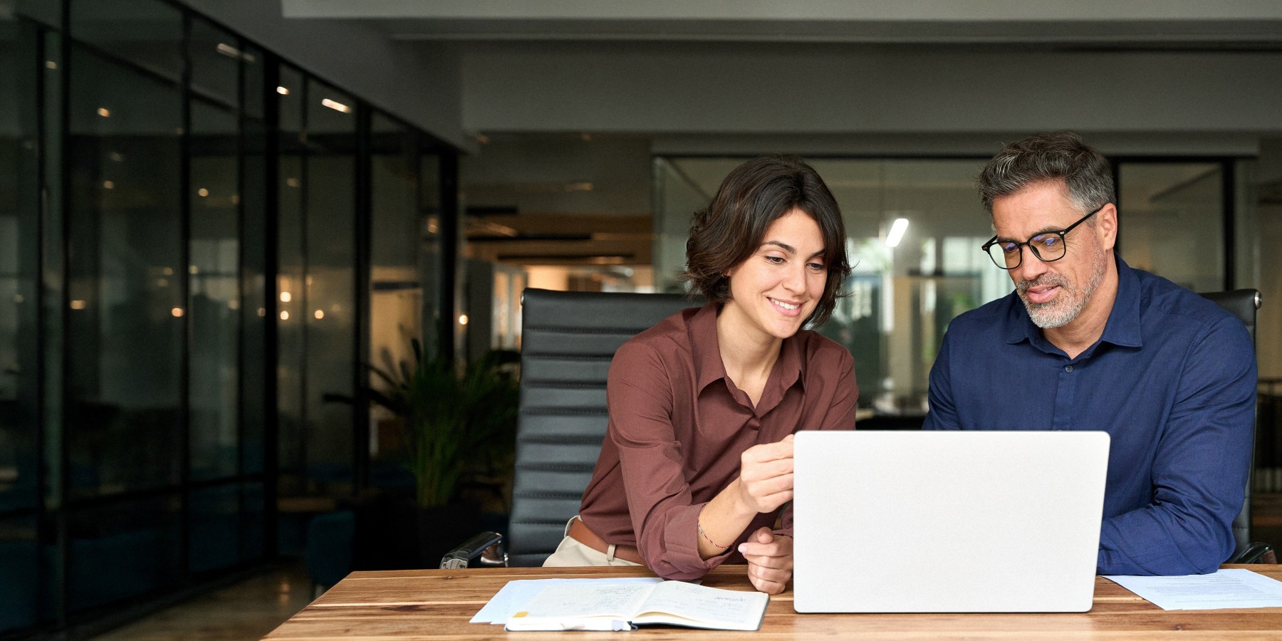 Zwei Personen besprechen gemeinsam Unterlagen und Laptop in einem modernen Büro – Symbolbild für Führungskräfte-Coaching, Teamcoaching und Unternehmensberatung bei Soulgrow