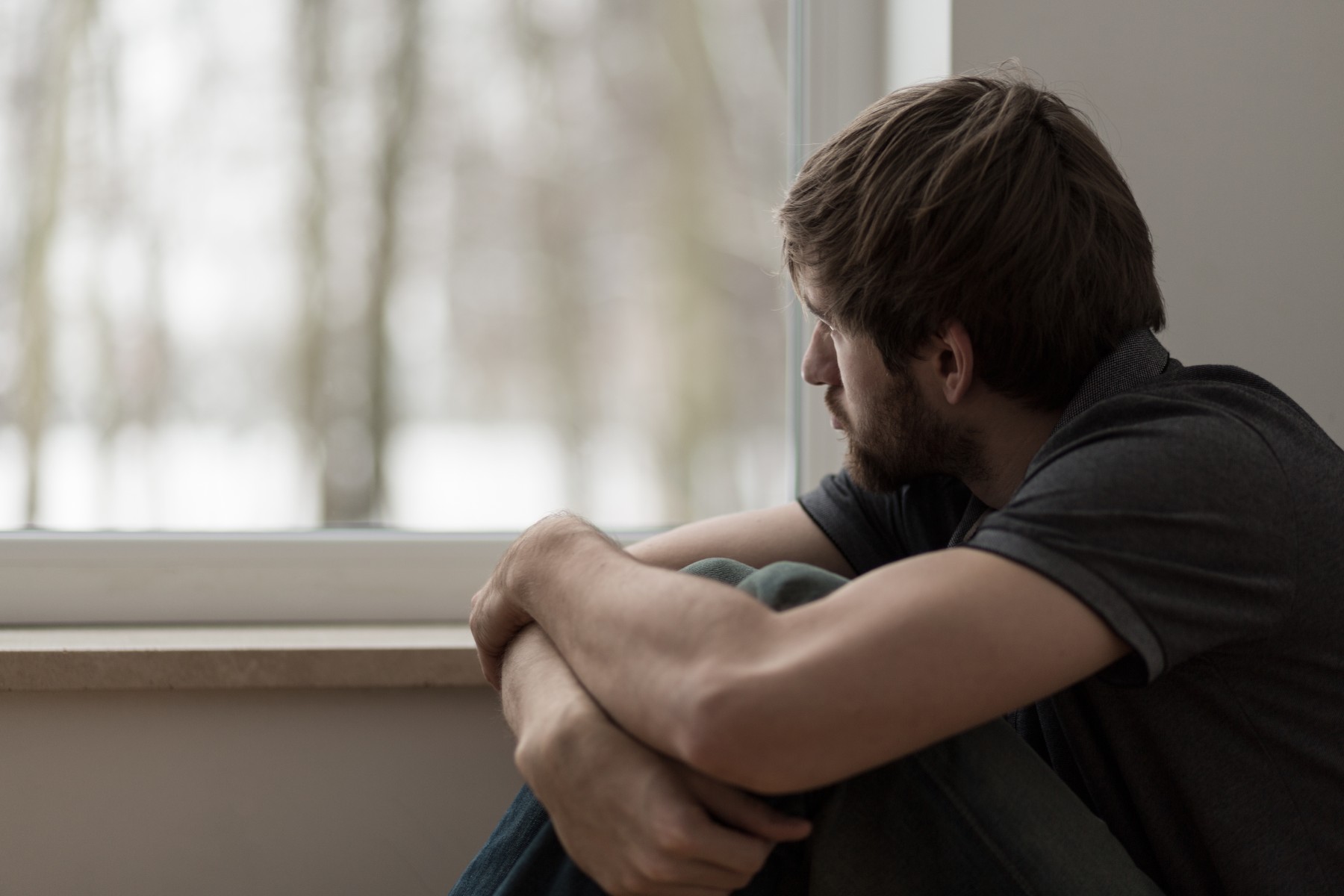 Nachdenklicher Mann sitzt am Fenster und schaut nach draußen