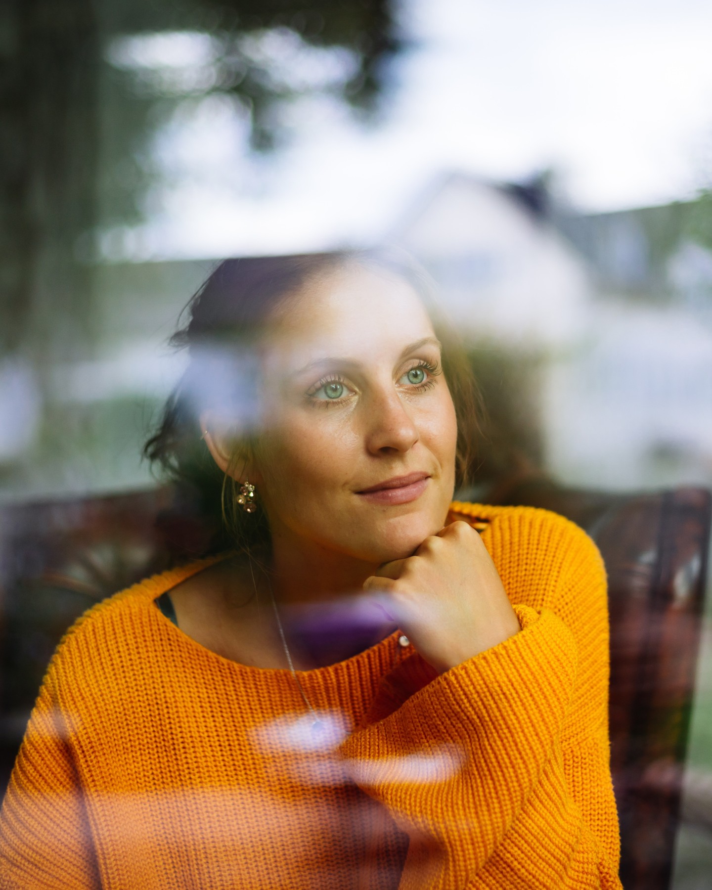 Nachdenkliche Frau sitzt hinter einer Fensterscheibe