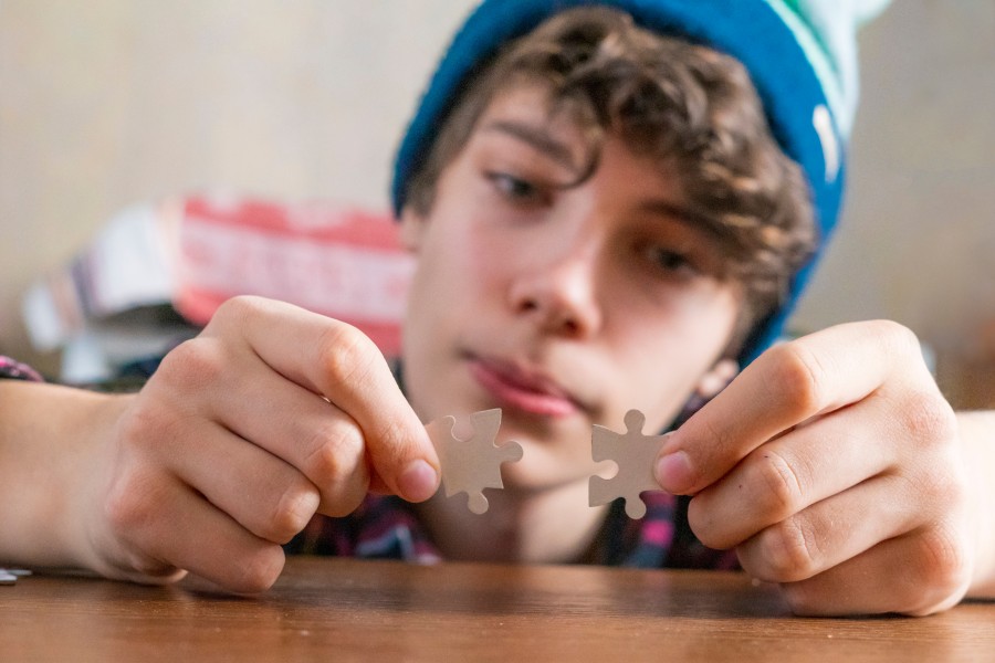 Junger Mensch hält zwei Puzzleteile als Symbol für Berufsorientierung und das Sortieren eigener Stärken und Interessen.